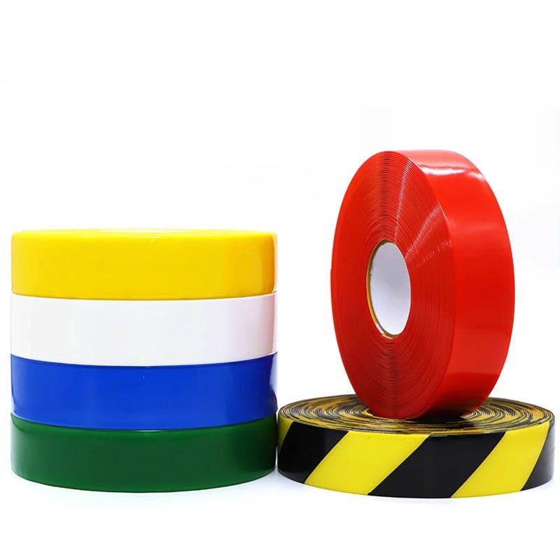 Heavy-duty floor marking tape range — stacked solid-color rolls, a red roll and a black and yellow diagonal stripe roll
